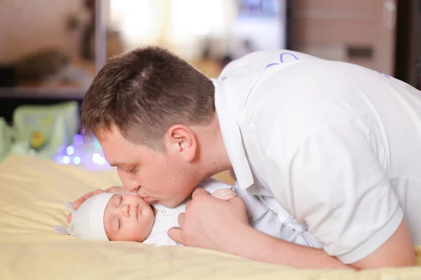 Молодой кавказский отец держит и целует новорожденного ребенка . — стоковое фото