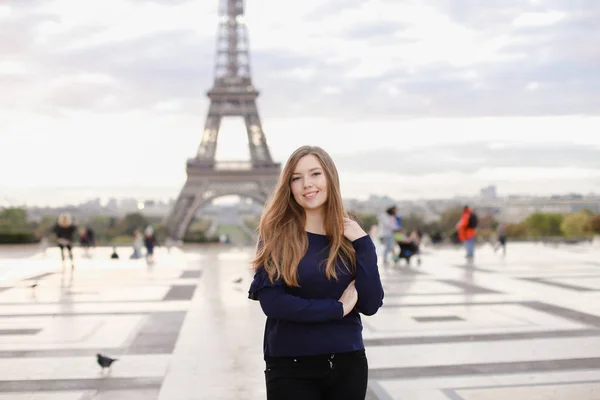 Vacker kvinna som står i Eiffeltornet bakgrunden i Paris. — Stockfoto