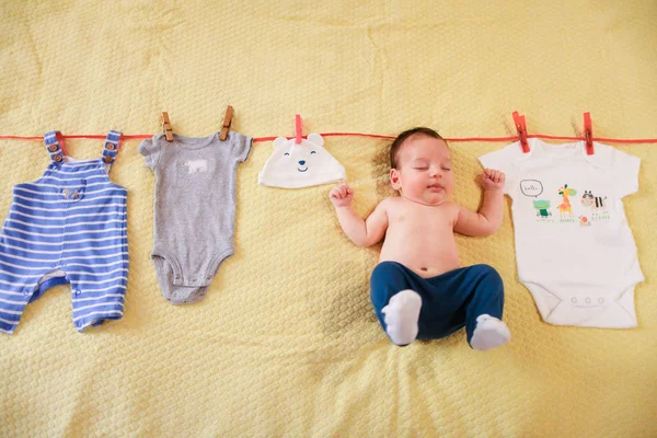 Petit bébé mignon suspendu avec des vêtements sur la corde . — Photo