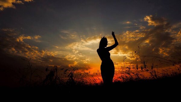 Female person dancing in steppe, silhouette in sunset background. Concept of dancing meditation and relaxing on nature.
