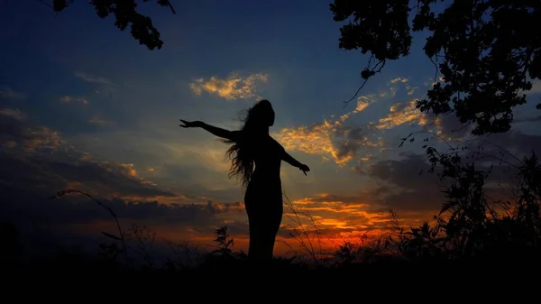 Dark female silhouette doing yoga asanas in evening sky background. — Stock Photo, Image