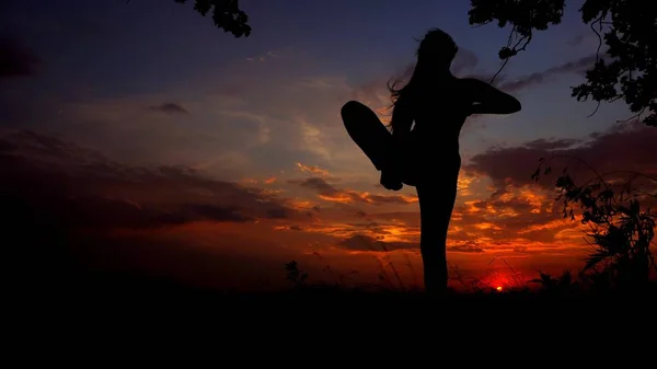 Youga asana e scuro silhouette femminile in sfondo cielo blu sera . — Foto Stock