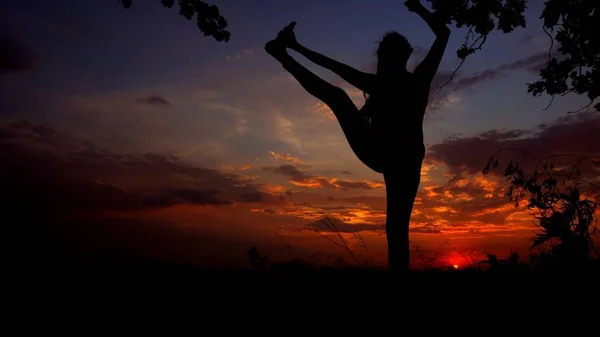 Silhouette femminile sullo sfondo del tramonto, donna che fa yoga prima di dormire . — Foto Stock