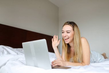 Genç kadın laptop ve hafta sonları sabah yatakta yatıyordu tarafından görüntülü arama yapma.