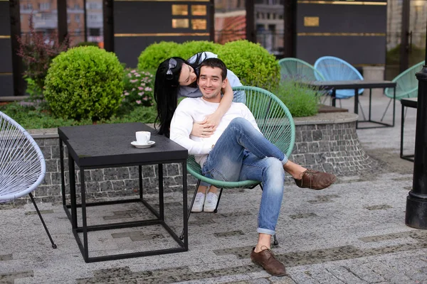 Жена целует мужа сидя в кресле в уличном кафе на улице . — стоковое фото