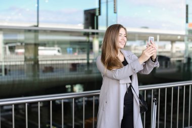 Beyaz işkadını smartphone valiz ve Havaalanı yakınında selfie yapma.