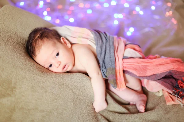 Little cute baby wrapped in blanket lying with twinkling glares in background. — Stock Photo, Image