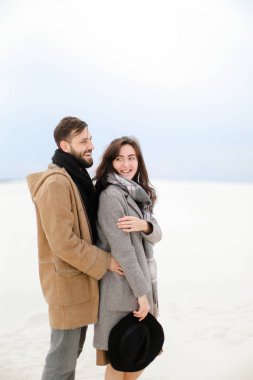 Sakal sarılma kadın kişi giyen gri ceket ve eşarp, Beyaz Kış tek sesli arka plan ile mutlu adam.