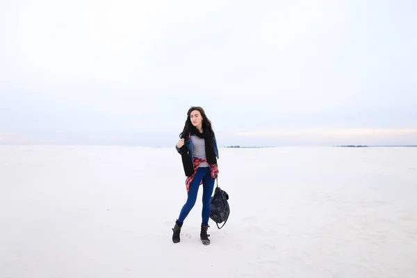 Bella donna che cammina su sfondo neve e indossa jeans con borsa . — Foto Stock