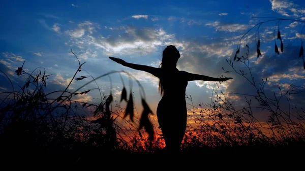 Weibliche dunkle Silhouette bei Asanas im abendlichen Steppenhintergrund. — Stockfoto