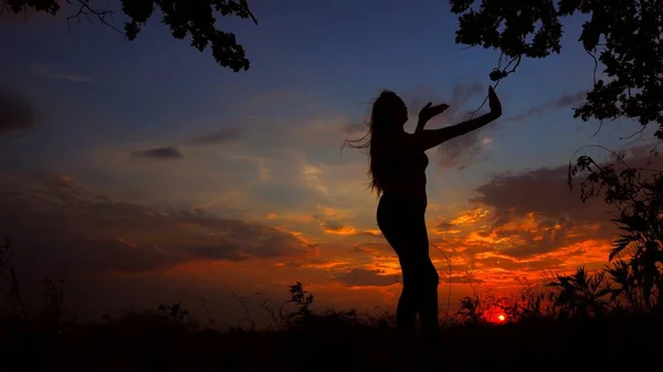 Silueta femenina meditando por la noche y haciendo yoga en el fondo del atardecer . —  Fotos de Stock