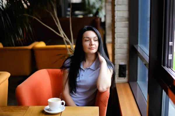 커피 한잔과 함께 카페에서 오렌지 안락의자에 앉아 여자. — 스톡 사진