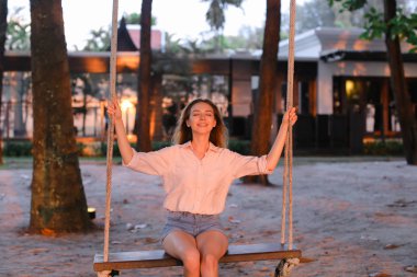 Salıncak kum üzerinde sürme genç kafkas kadın arka planda evler.