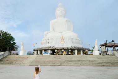 Küçük kız beyaz Phuket Buda heykeli bakarak.