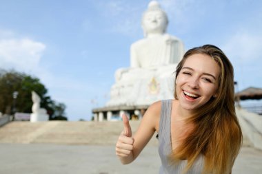 Phuket Buda heykelinin arka planda beyaz kadın gösteren başparmak, gülümseyen genç.