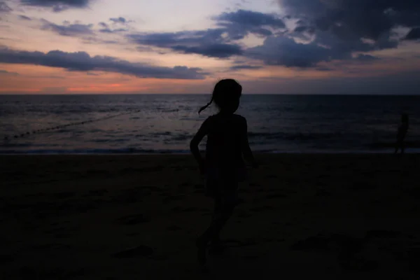 夕方の日没で母と一緒に海岸に小さな女の子シルエット. — ストック写真