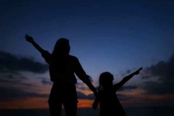 Черный силуэт женщины и маленькой девочки, идущих в вечернее время, закат фона . — стоковое фото