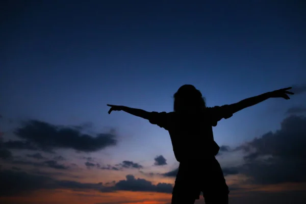 Silhueta preta de jovem mulher no pôr do sol céu azul escuro com nuvens de fundo . — Fotografia de Stock