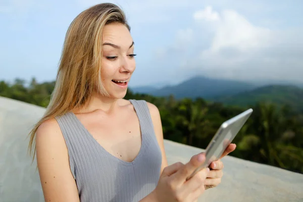 Joven mujer alegre utilizando tableta en el fondo de las montañas . — Foto de Stock