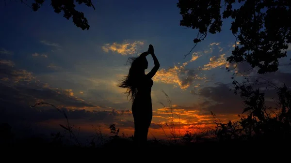 Black female silhouette doing yoga and meditating in evening sky background. — Stock Photo, Image