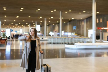 Havaalanı salonunda yürüyüş ve bakarak gri ceket giyen kadın.