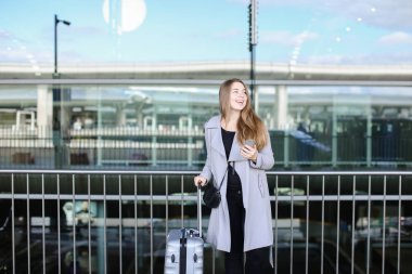 Valiz ve smartpone Havaalanı yakınında duran Amerikan kadın kişi.