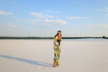 Kumsalda dans mayo ve plaj elbise giyen genç kadın.