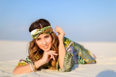 Beyaz kum üzerinde yalan yeşil plaj elbise giyen genç güzel kadın.