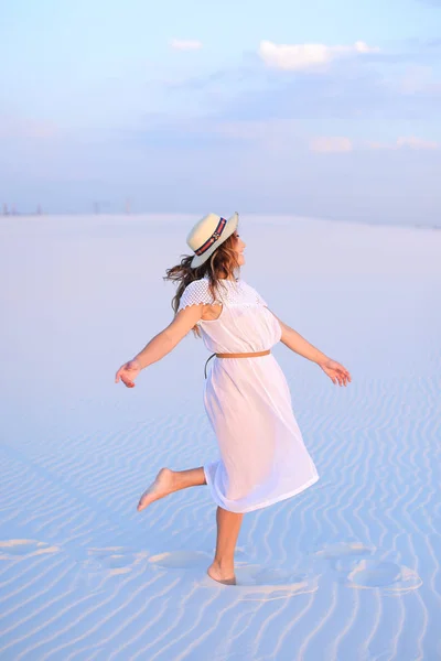 Молода жінка в сукні і капелюсі стоїть на білому піску — стокове фото