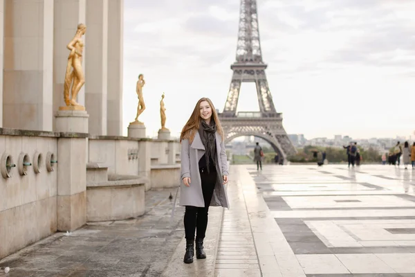 Eine kleine Frau steht auf dem Trocadero-Platz in der Nähe vergoldeter Statuen und des Eiffelturms. — Stockfoto