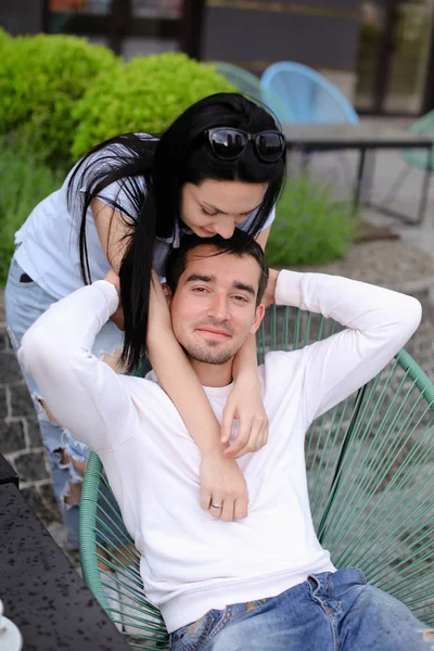 Esposa beijando marido sentado na cadeira no café de rua fora . — Fotografia de Stock