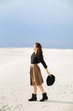 Kar beyaz güzel kadın fotoğraf modeli ayakta ve etek ve siyah bluz giyiyor. şapka tutmak.