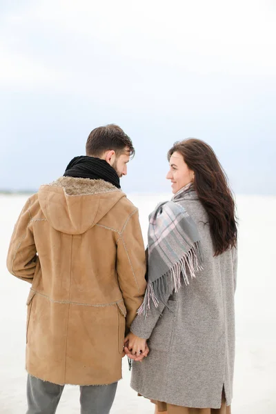 Kaukasisches glückliches Paar, das auf winterlichem Schnee wandelt, Mäntel und Schals trägt. — Stockfoto