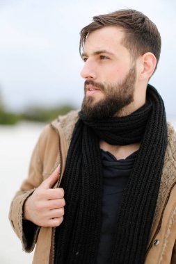 Ceket ve siyah eşarp ayakta beyaz kış arka planda giyen sakallı Genç beyaz adam portresi kapatın.