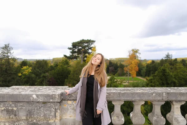 Ragazza sorridente in piedi vicino ringhiera in cemento con sfondo albero . — Foto Stock