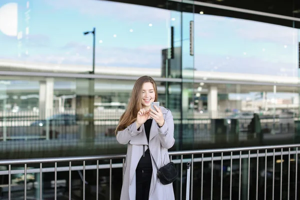 Vacker affärskvinna att göra selfie av smartphone nära valise och flygplats. — Stockfoto