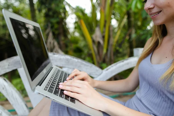 Menina sorrindo jovem usando laptop, palmas no fundo . — Fotografia de Stock