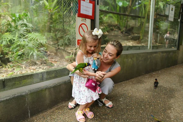 젊은 행복 한 어머니와 작은 딸 태국에서 밖에 서 앵무새와 함께 즐기는. — 스톡 사진