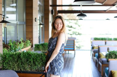 Kız yeşil palnts yakınındaki kafede ayakta.