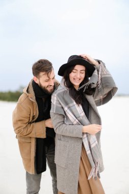 Gülümseyen kız ve kat ve kış kar arka planda duran tulum giyen sakallı.