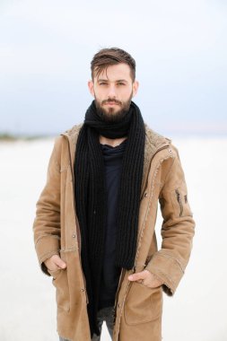Paltonu ve kaşkolünü beyaz kar arka planda duran giyen sakallı Avrupa şık erkek kişi.