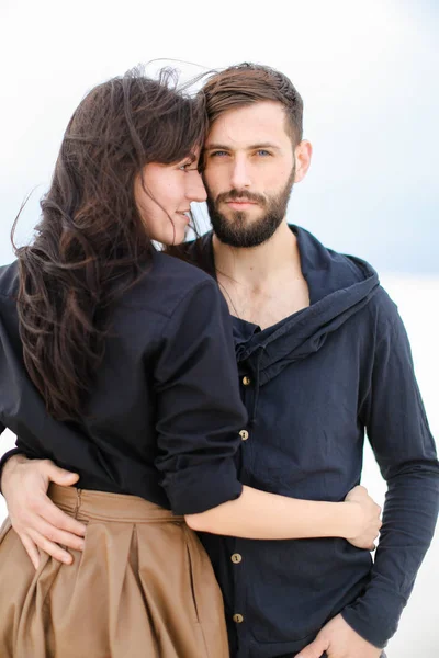 Jovem casal caucasiano abraçando uns aos outros e vestindo roupas elegantes em fundo de inverno monofônico branco . — Fotografia de Stock