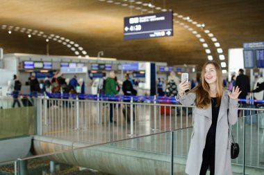 Sevimli kadın smartphone ön kamera havaalanında selfie yapma.