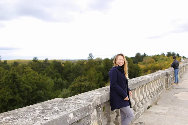 Kobieta stojąc w pobliżu betonowe balustrady, z tle drzewa. — Zdjęcie stockowe