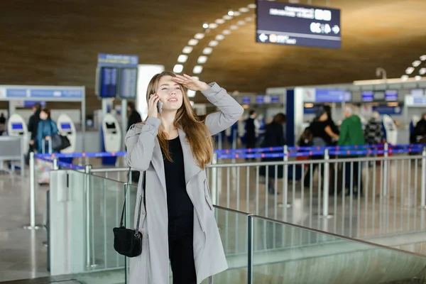 Peson kobiece rozmowy za pomocą smartfonów i szuka przyjaciela na lotniska. — Zdjęcie stockowe