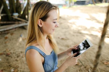 Tablet kum arka planda kullanan genç kız.