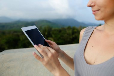 Tablet ountains arka planda kullanan genç beyaz kadın kişi.