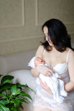 Yeni doğan bebek tutan beyaz elbise giyen genç kadın kişi.