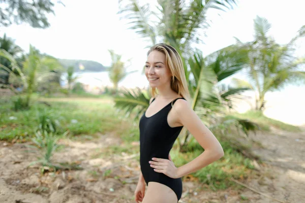 Młoda kobieta ubrana w czarny kostium kąpielowy stojący na piasku. — Zdjęcie stockowe