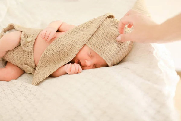 Female hand touching sleeping newborn baby in crocheted clothes. — Stock Photo, Image